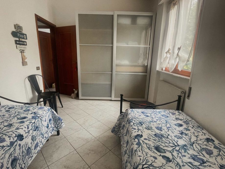 Gemütliches Schlafzimmer mit zwei Betten und Blick auf den Garten.